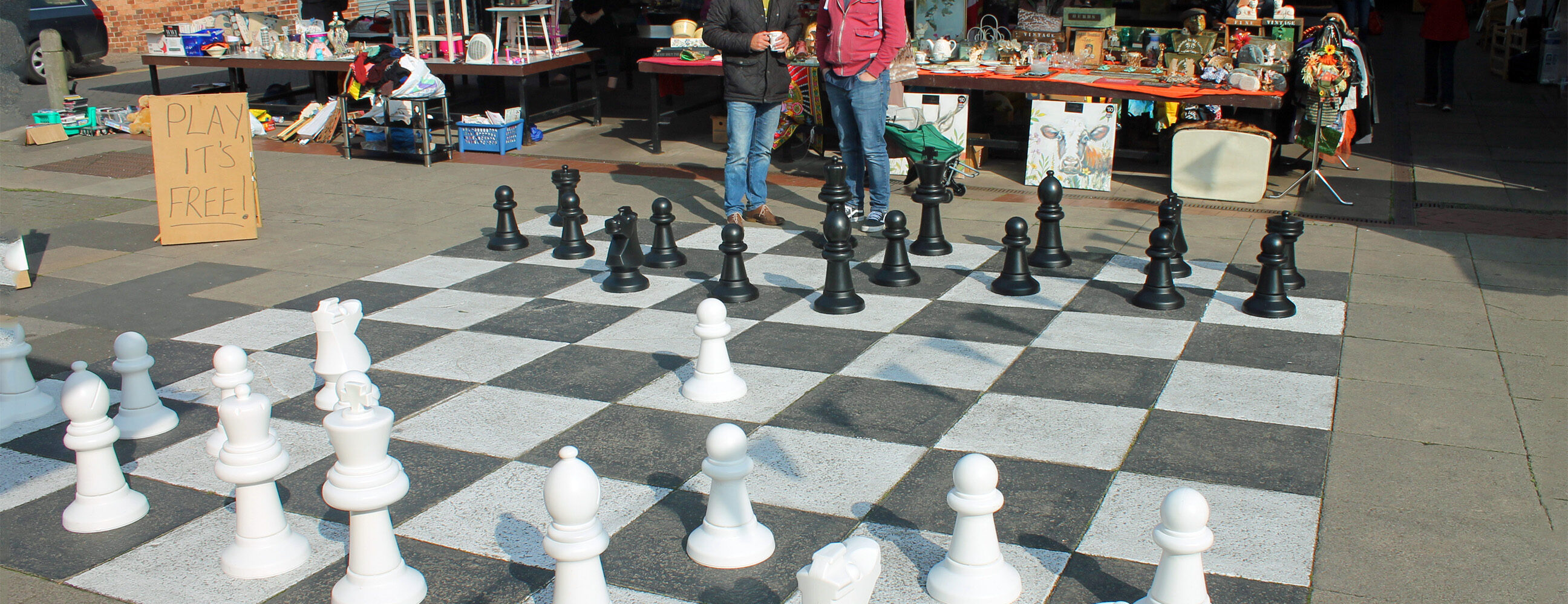 Two men playing giant chess at a market.